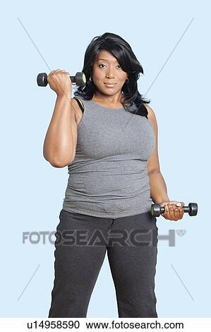 Portrait of mixed race woman lifting weights over blue background View Large Photo Image Stock Image - Portrait of mixed race woman lifting weights over blue background. Fotosearch