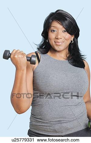 Portrait of mixed race woman lifting weights over blue background View Large Photo Image Stock Image - Portrait of mixed race woman lifting weights over blue background. Fotosearch