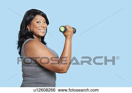 Portrait of mixed race woman lifting weights over blue background View Large Photo Image Stock Photograph - Portrait of mixed race woman lifting weights over blue background. Fotosearch