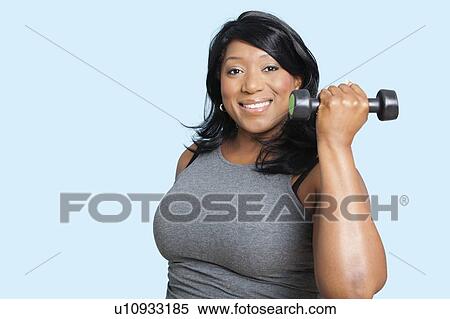 Portrait of mixed race woman lifting weights over blue background View Large Photo Image Stock Photography - Portrait of mixed race woman lifting weights over blue background. Fotosearch