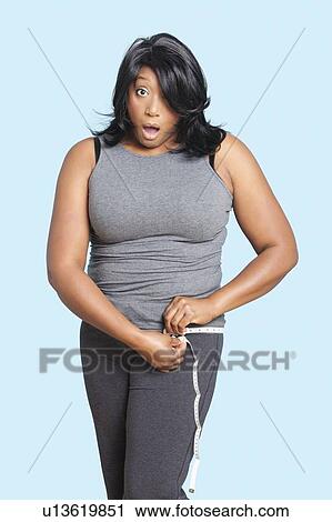 Portrait of overweight mixed race woman measuring waist over blue background View Large Photo Image Stock Image - Portrait of overweight mixed race woman measuring waist over blue background. Fotosearch