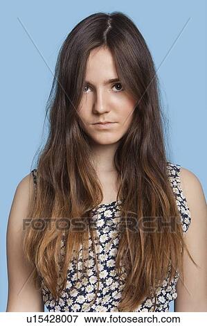 Portrait of serious young woman over blue background View Large Photo Image Stock Photo - Portrait of serious young woman over blue background. Fotosearch