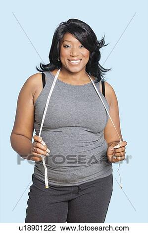 Portrait of smiling mixed race woman with measuring tape over blue background View Large Photo Image Stock Image - Portrait of smiling mixed race woman with measuring tape over blue background. Fotosearch