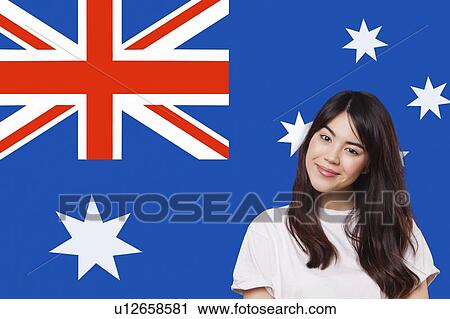 Stock Image - Portrait of smiling mixed race young woman against Australian flag. Fotosearch