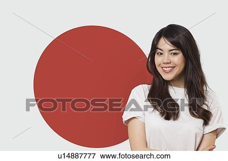 Stock Photo - Portrait of smiling mixed race young woman against Japanese flag. Fotosearch