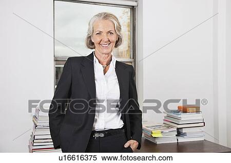 Portrait of smiling senior businesswoman with stack of books on desk in office View Large Photo Image Stock Photography - Portrait of smiling senior businesswoman with stack of books on desk in office. Fotosearch