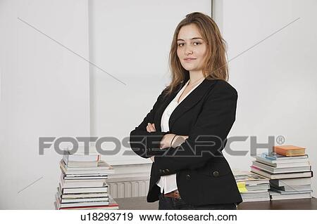 Portrait of smiling young businesswoman with stack of books on desk in office View Large Photo Image Stock Photo - Portrait of smiling young businesswoman with stack of books on desk in office. Fotosearch