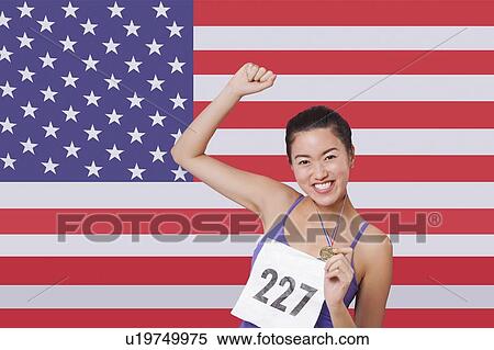 Portrait of smiling young female medalist standing against American flag View Large Photo Image Stock Photography - Portrait of smiling young female medalist standing against American flag. Fotosearch
