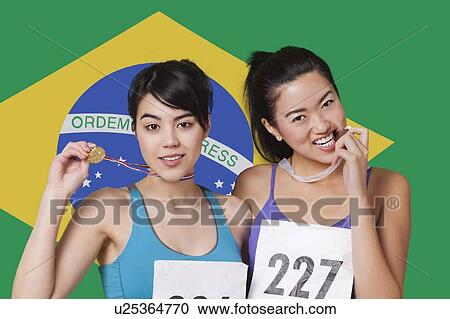 Portrait of smiling young medalists standing against Brazilian flag View Large Photo Image Stock Image - Portrait of smiling young medalists standing against Brazilian flag. Fotosearch