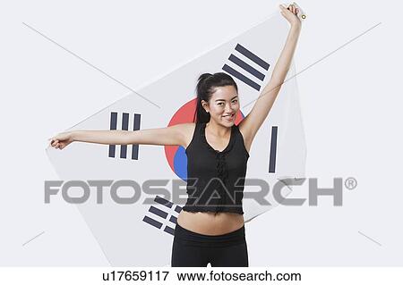 Stock Photo - Portrait of smiling young woman holding Korean flag over white background. Fotosearch
