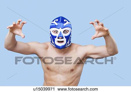 Stock Image - Portrait of topless man in wrestling mask gesturing over gray background. Fotosearch