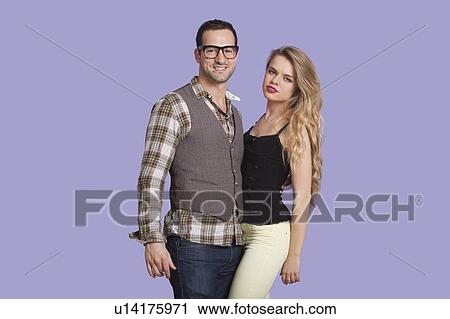 Stock Image - Portrait of young couple against purple background. Fotosearch