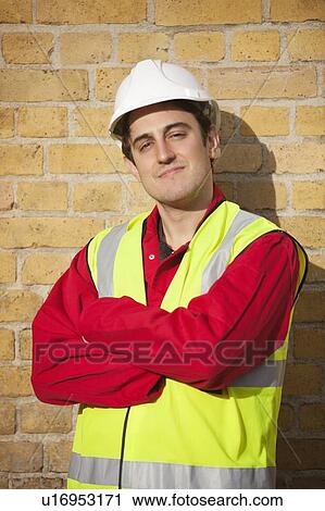 Portrait of young man wearing safety vest and hardhat against brick wall View Large Photo Image Stock Image - Portrait of young man wearing safety vest and hardhat against brick wall. Fotosearch