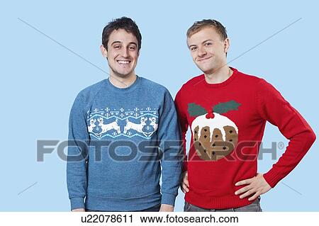 Portrait of young men in warm clothing standing against blue background View Large Photo Image Stock Image - Portrait of young men in warm clothing standing against blue background. Fotosearch