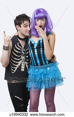 Stock Image - Portrait of young punk man with surprised young woman over white background. Fotosearch