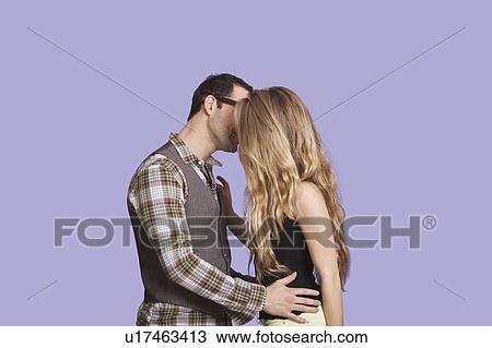 Side view of young couple kissing over purple background View Large Photo Image Stock Image - Side view of young couple kissing over purple background. Fotosearch