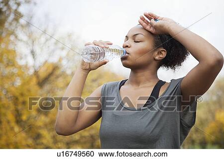 Sporty young woman drinking water in park View Large Photo Image Stock Image - Sporty young woman drinking water in park. Fotosearch