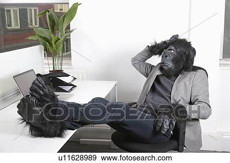 Stock Photo - Thoughtful young man in gorilla costume resting at office. Fotosearch