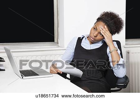 Tired young businesswoman in front of laptop at desk in office View Large Photo Image Picture - Tired young businesswoman in front of laptop at desk in office. Fotosearch