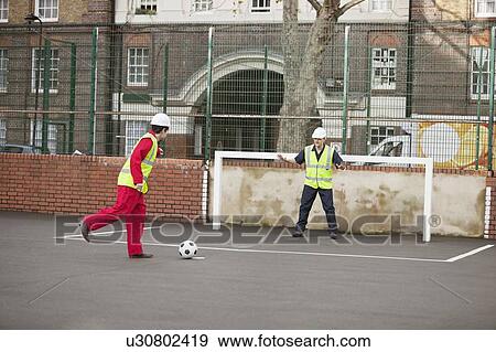Two manual workers playing football View Large Photo Image Stock Photo - Two manual workers playing football. Fotosearch