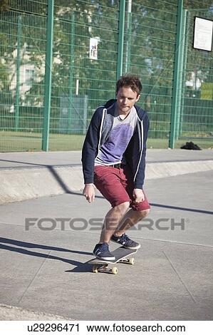 Young man skateboarding on road View Large Photo Image Stock Image - Young man skateboarding on road. Fotosearch