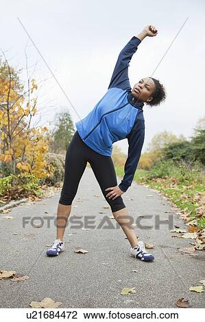 Young woman stretching in park View Large Photo Image Stock Image - Young woman stretching in park. Fotosearch