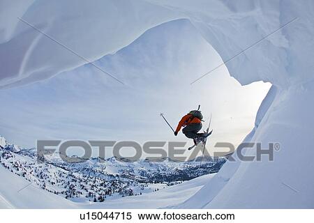 A Young Male Freeskier Jumps Off A Cornice While Backcountry