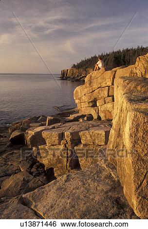 Acadia, Acadia National Park, Maine, Atlantic Ocean, A woman sits on the rocky coastline looking out at the ocean in the early morning light in Acadia Nat'l Park in the state of Maine. View Large Photo Image Stock Photograph - Acadia, Acadia National Park, Maine, Atlantic Ocean, A woman sits on the rocky coastline looking out at the ocean in the early morning light in Acadia Nat'l Park in the state of Maine.. Fotosearch