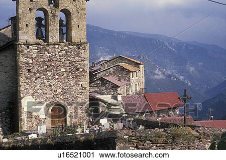 Stock Image -  Alps, France, Europe, A picturesque village of Roure made of stone built on the mountainside in the the French Alps in Alpes-Maritimes. Church made of stone with bell tower and houses with red roofs.. Fotosearch