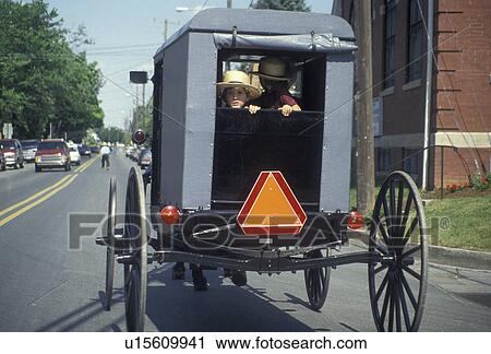 Stock Image -  Amish, Amish buggy, Amish Country, Lancaster County, traffic, Pennsylvania, Amish child looking out the back of an Amish buggy on a road in Pennsylvania Dutch Country in Lancaster County in the state of Pennsylvania.. Fotosearch