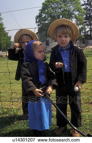 Stock Photo -  amish, Amish Country, children, Lancaster County, Pennsylvania, Three Amish children (one girl and two boys) stand by a fence looking at a dead bird in one of the boy's hands on an Amish farm in Pennsylvania Dutch Country in Lancaster County in the state. Fotosearch