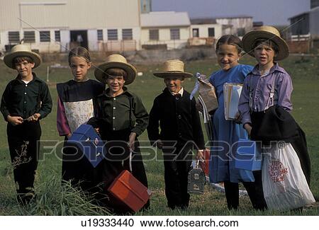 Stock Image -  Amish, children, Pennsylvania, Lancaster County, White Horse, A group of Amish children in front a farm waiting for the Buggy Bus going to school in Lancaster County. The boys are wearing traditional straw hats.. Fotosearch