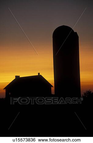 Stock Photograph -  amish, farm, Amish country, Lancaster County, Pennsylvania, Pennsylvania Dutch Country, A silhouette of an Amish barn and silo at sunset in Lancaster in the state of Pennsylvania. . Fotosearch