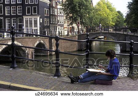 Picture -  Amsterdam, Netherlands, Europe, Artist painting picture of old houses in downtown Amsterdam from a bridge across a canal.. Fotosearch