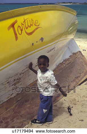 Anguilla, Caribbean, Caribbean Islands, Young local boy standing next to yellow fishing boat on the beach at Island Harbor on the island of Anguilla (a british territory). View Large Photo Image Picture - Anguilla, Caribbean, Caribbean Islands, Young local boy standing next to yellow fishing boat on the beach at Island Harbor on the island of Anguilla (a british territory).. Fotosearch