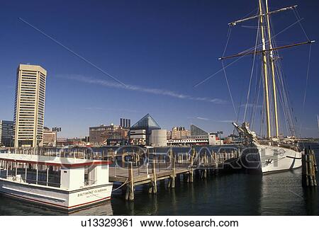 Stock Image -  Baltimore harbor, Maryland, skyline, Tour boats docked at Baltimore's scenic Inner Harbor and view of the downtown skyline.. Fotosearch