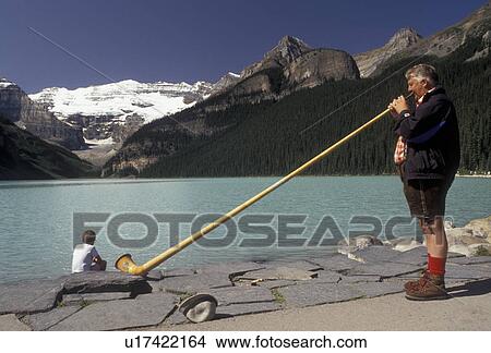 Banff National Park, alpine horn, Lake Louise, Alberta, Canada, Canadian Rockies, Rocky Mountains, A man dressed in lederhosen plays a long Alpine Horn on beautiful Lake Louise with the snow-capped mountains in the distance in Banff National Park in the View Large Photo Image Picture - Banff National Park, alpine horn, Lake Louise, Alberta, Canada, Canadian Rockies, Rocky Mountains, A man dressed in lederhosen plays a long Alpine Horn on beautiful Lake Louise with the snow-capped mountains in the distance in Banff National Park in the . Fotosearch