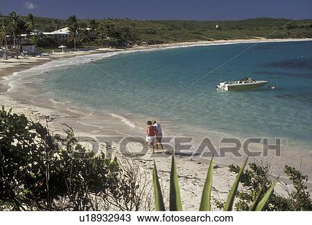 Stock Image -  beach, Antigua, Caribbean, Caribbean Islands, People walking on the beach on Half Moon Bay Beach on the island of Antigua (a British Commonwealth member). . Fotosearch