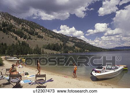 Stock Image -  beach, lake, Sawtooth National Recreation Area, Idaho, Sawtooth Range, Rocky Mountains, People enjoying a warm summer day on the calm waters of Lake Altura in Sawtooth National Recreation Area in the state of Idaho.. Fotosearch