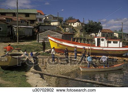 Stock Image -  boat, Chile, Fishermen launching a renovated bright yellow, white and red fishing boat into the water in Amargos in the South-Central Region in Chile. . Fotosearch