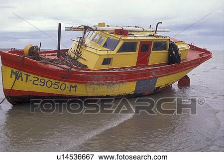 Stock Photo -  boat, Patagonia, Argentina, A red and yellow fishing boat anchored on the beach at low tide at Rio Gallegos . Fotosearch