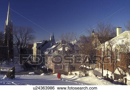 Canada, Quebec, Man walks down snow covered hill overlooking houses from de Ramparts in Old Quebec City in winter., View Large Photo Image Stock Photograph - Canada, Quebec, Man walks down snow covered hill overlooking houses from de Ramparts in Old Quebec City in winter., . Fotosearch