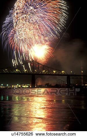 Stock Photograph -  Canada, Quebec, Montreal, Firework display from the Benson & Hedges International Firework Competition reflects on the St. Lawrence River (Fleuve Saint-Laurent) at night in Montreal. Pont Jacques Cartier . Fotosearch