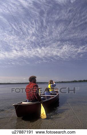 Stock Image -  canoe, canoeing, family, lake, Alexandria, Minnesota, Father and children paddle a canoe on the calm water of Maple Lake in Alexandria in the state of Minnesota.. Fotosearch
