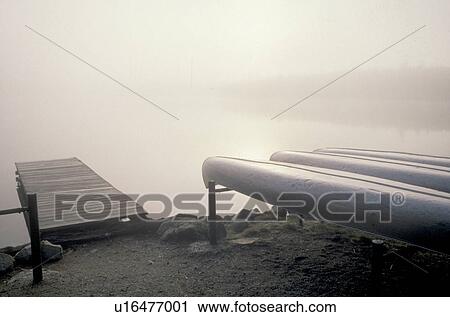 Stock Image -  canoe, fog, Maine, Baxter State Park, Dock and canoes in early morning fog on Daicey Pond in Baxter State Park in the fall.. Fotosearch