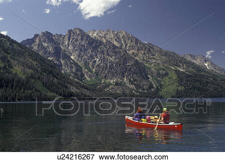 Stock Photo -  canoe, Grand Teton National Park, Lake Jenny, Wyoming, Grand Teton, Rocky Mountains, Grand Teton Mountains, A family paddles their red canoe on Lake Jenny with a view of the majestic Teton Mountains in front of them in Grand Teton National Park in the st. Fotosearch