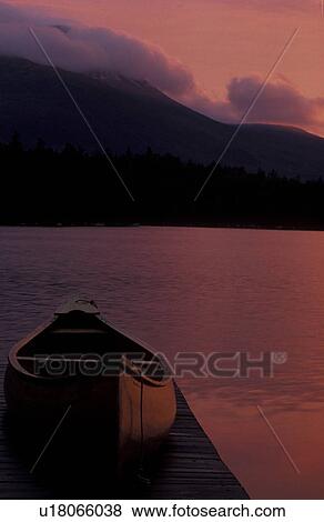 Stock Photo -  canoe, sunrise, sunset, mountain, lake, Baxter State Park, Maine, Mt. Katahdin, [Sunrise, sunset] on Daicey Pond in early morning at Baxter State Park. Canoe rest on the dock of the lake. Mt. Katahdin in the background.. Fotosearch