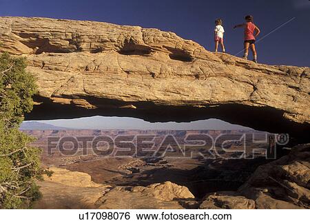 Stock Photograph -  Canyonlands, Canyonlands National Park, Utah, Mother and daughter (6 years old) stand on top of Mesa Arch a natural rock formation in Canyonlands Nat'l Park in the state of Utah. . Fotosearch