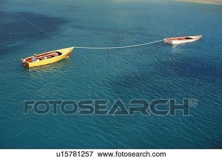 Stock Photo -  Caribbean, Canouan, Grenadine Islands, Caribbean Islands, Two small boats and one fisherman drifting together in the blue green waters of the caribbean off the island of Canouan in the St. Vincent Grenadines (a British Commonwealth member).. Fotosearch