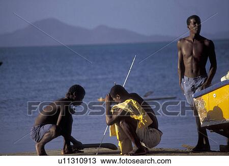 Stock Image -  Caribbean, Union Island, Grenadine Islands, Caribbean, Caribbean Islands, Three local black fishermen working together on the beach on Union Island in the St. Vincent Grenadines (a British Commonwealth member).. Fotosearch